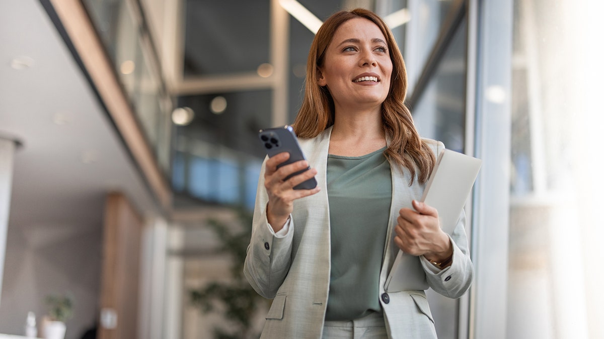 bus iness woman with phone and portfolio in office